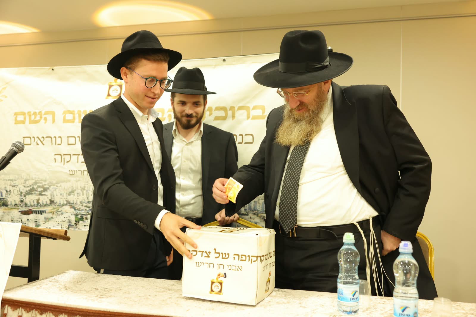 נתינת שטר לקופת הצדקה בעמידה ליד השולחן