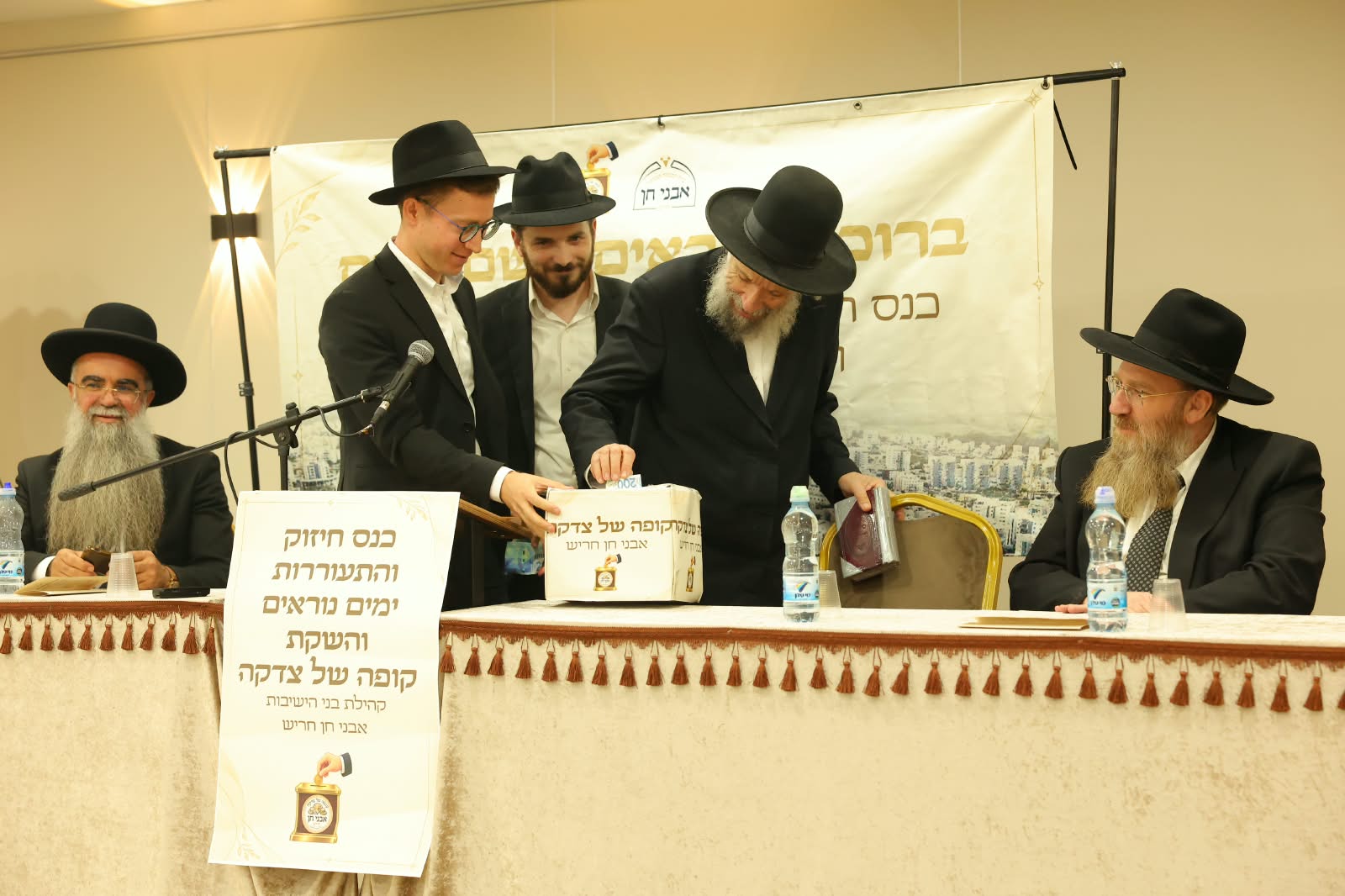 הגאון הגדול רבי יצחק קולדצקי שליט״א תורם לקופת הצדקה ׳אבני חן׳ על שולחן הכבוד