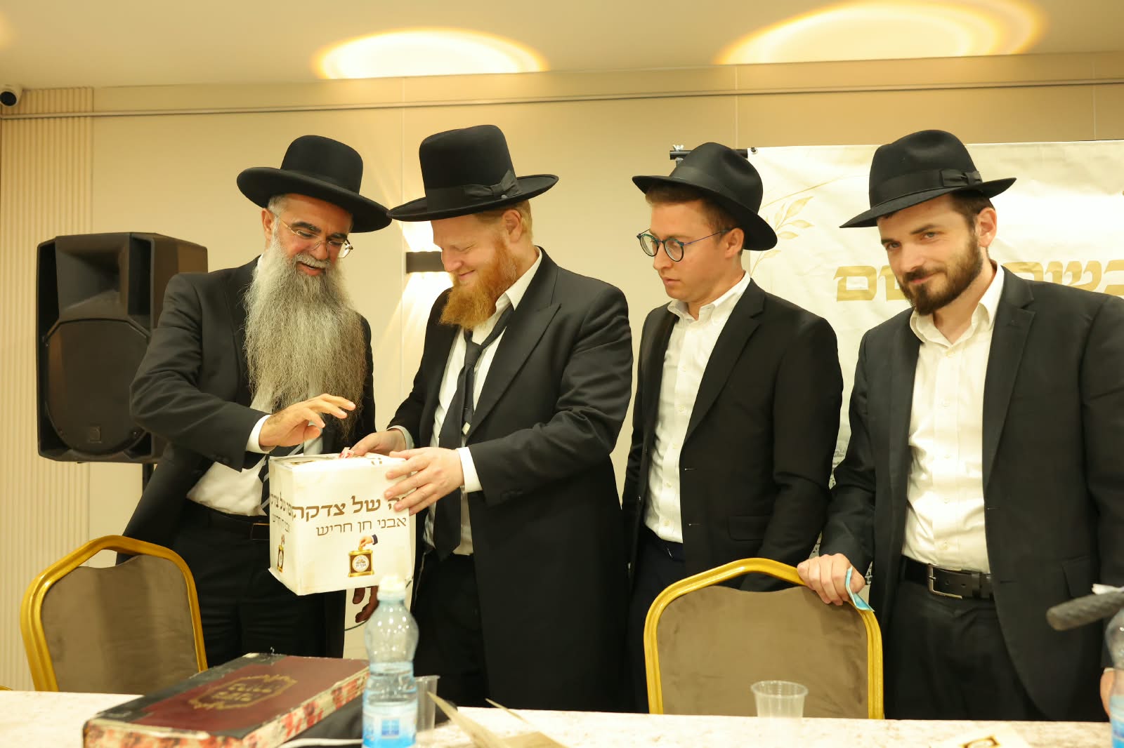 רב העיר הרב זיגדון שליט״א ומשתתפים נוספים סביב קופת הצדקה